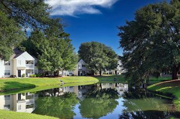 A serene lake in front of a building surrounded by trees.